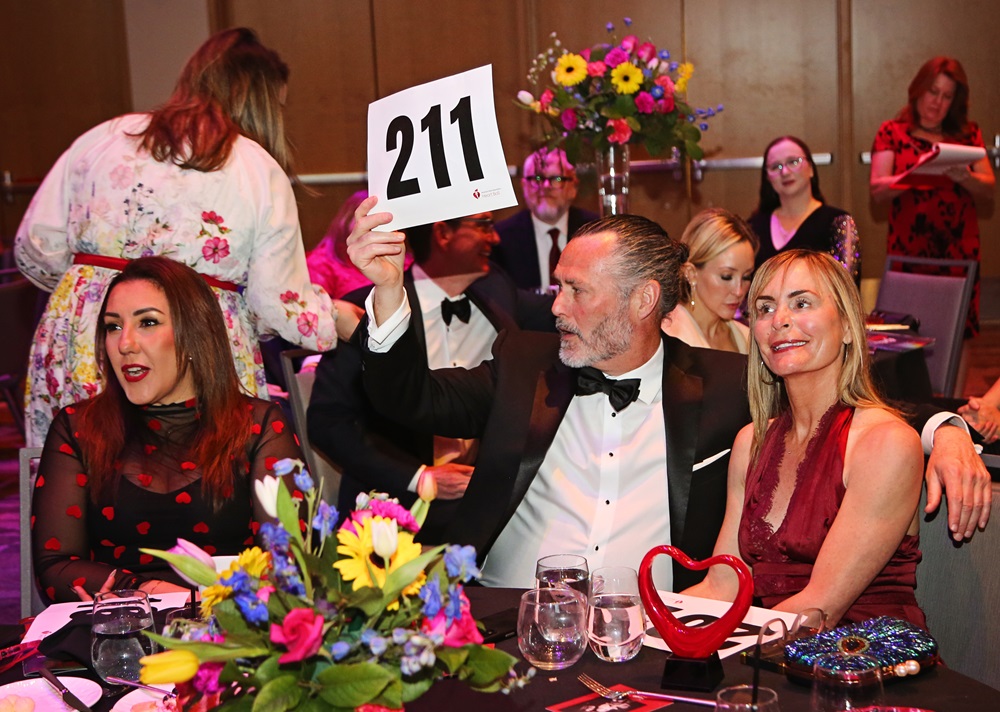 Seated couple holding up bidder number 211.